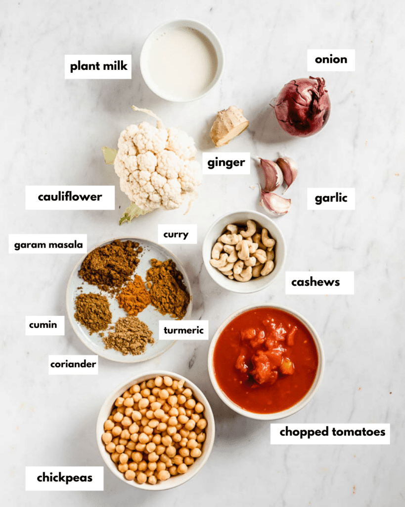 ingredients needed for cauliflower chickpea masala: chickpeas, chopped tomatoes, turmeric, coriander, cumin, garam masala, curry, cashews, garlic, cauliflower, onion, ginger