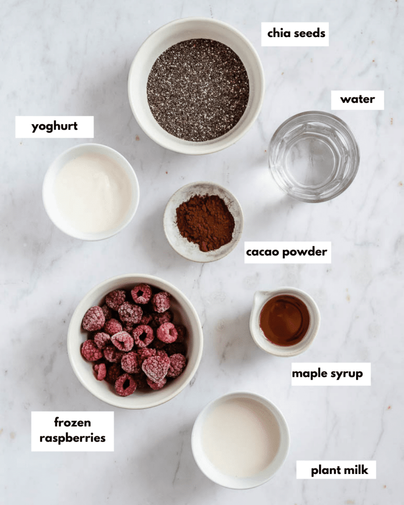 all ingredints needed for raspberry chocolate chia pudding: frozen raspberries, plant milk, maple syrup, cacao powder, yoghurt, water, chia seeds