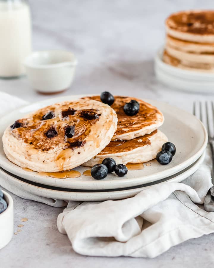 3 protein pancakes on a plate drizzle with maple syrup