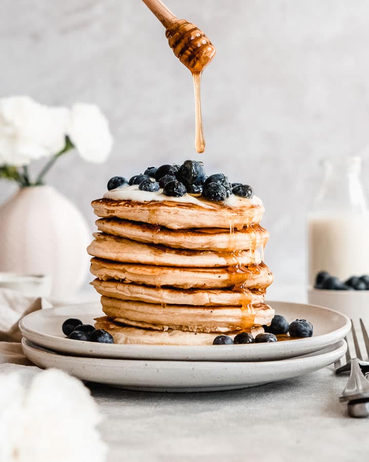 stack of protein pancakes without banana topped with yogurt, blueberries and maple syrup.
