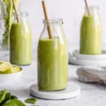3 glass jars of celery cucumber smoothies with a straw.