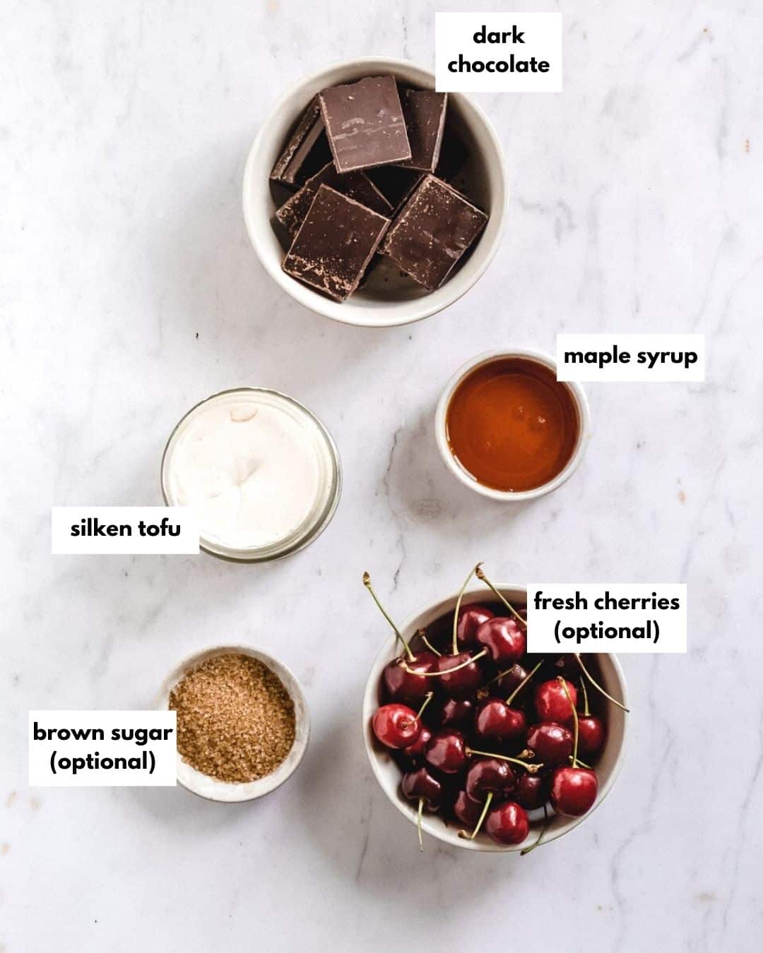 all ingredients needed for chocolate cherry dessert: dark chocolate, maple yrup, silken tofu, bworn sugar, fresh cherries.