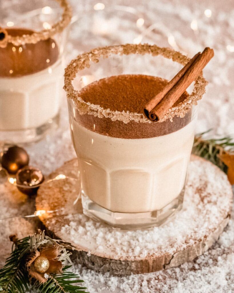 2 glasses of almond milk eggnog topped with a cinnamon stick