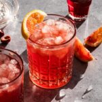cranberry mocktail topped with ice cubes and a slice of orange