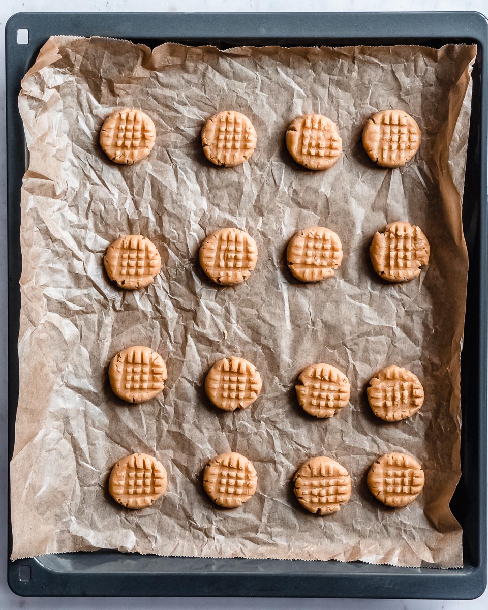 peanubutter cookies on a baking tray lined with parchment paper ready to be baked