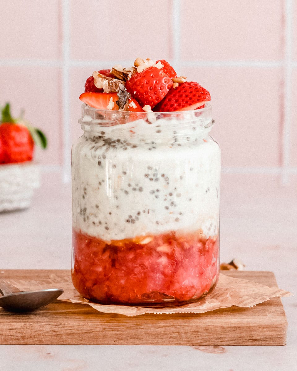 glas jar filled ⅓ added with muddled strawberries, and ⅔ overnight oats with water and topped with fresh strawberries and nuts