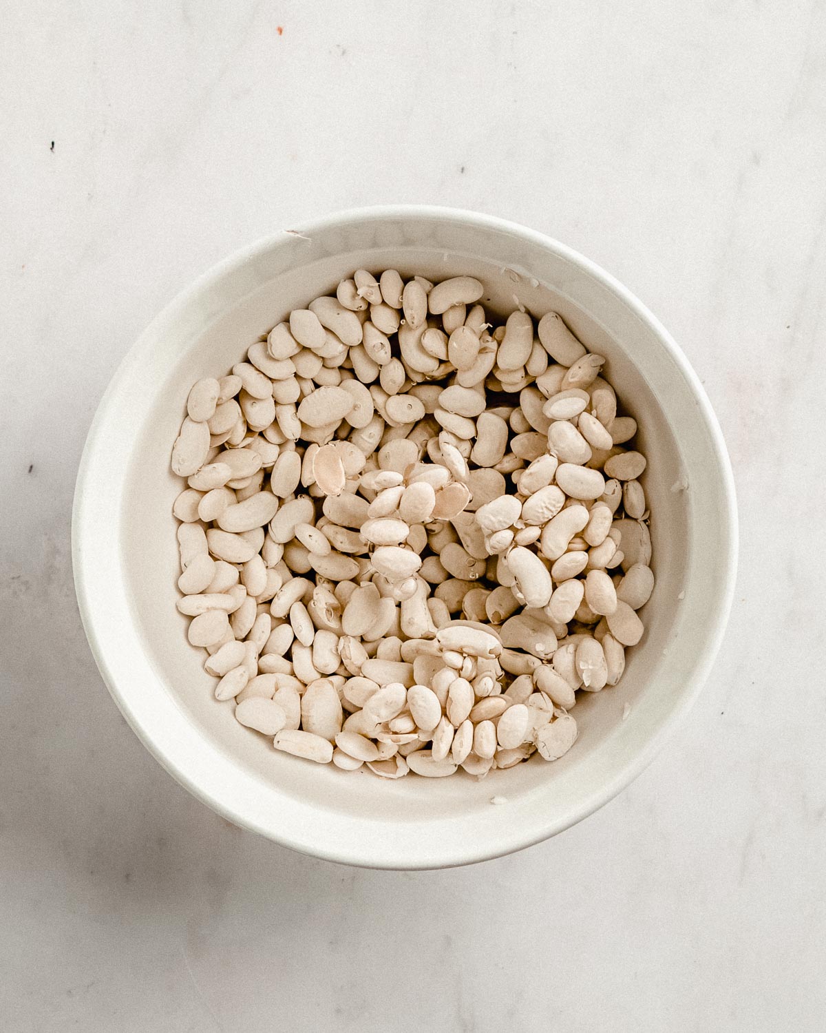 dried beans covered with water in a big ceramic bowl.