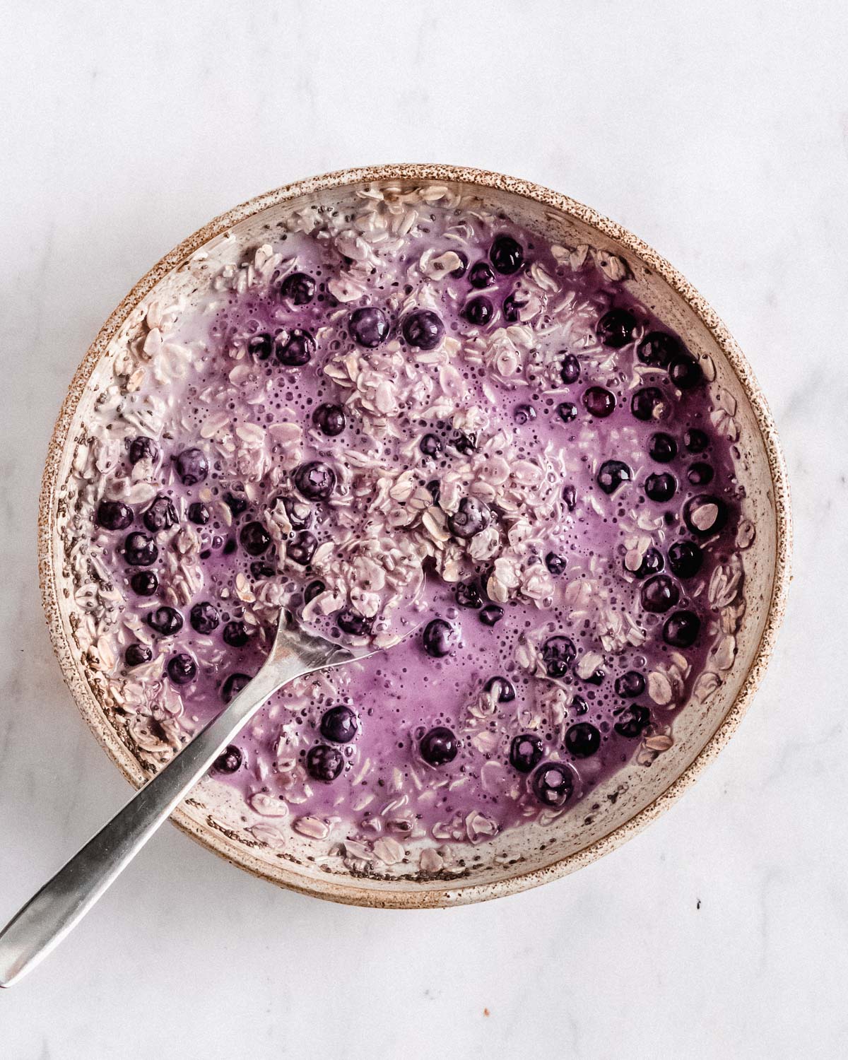 plant milk, yogurt, rolled oats, chia seeds, maple syrup and frozen berries in a granola bowl mixed together