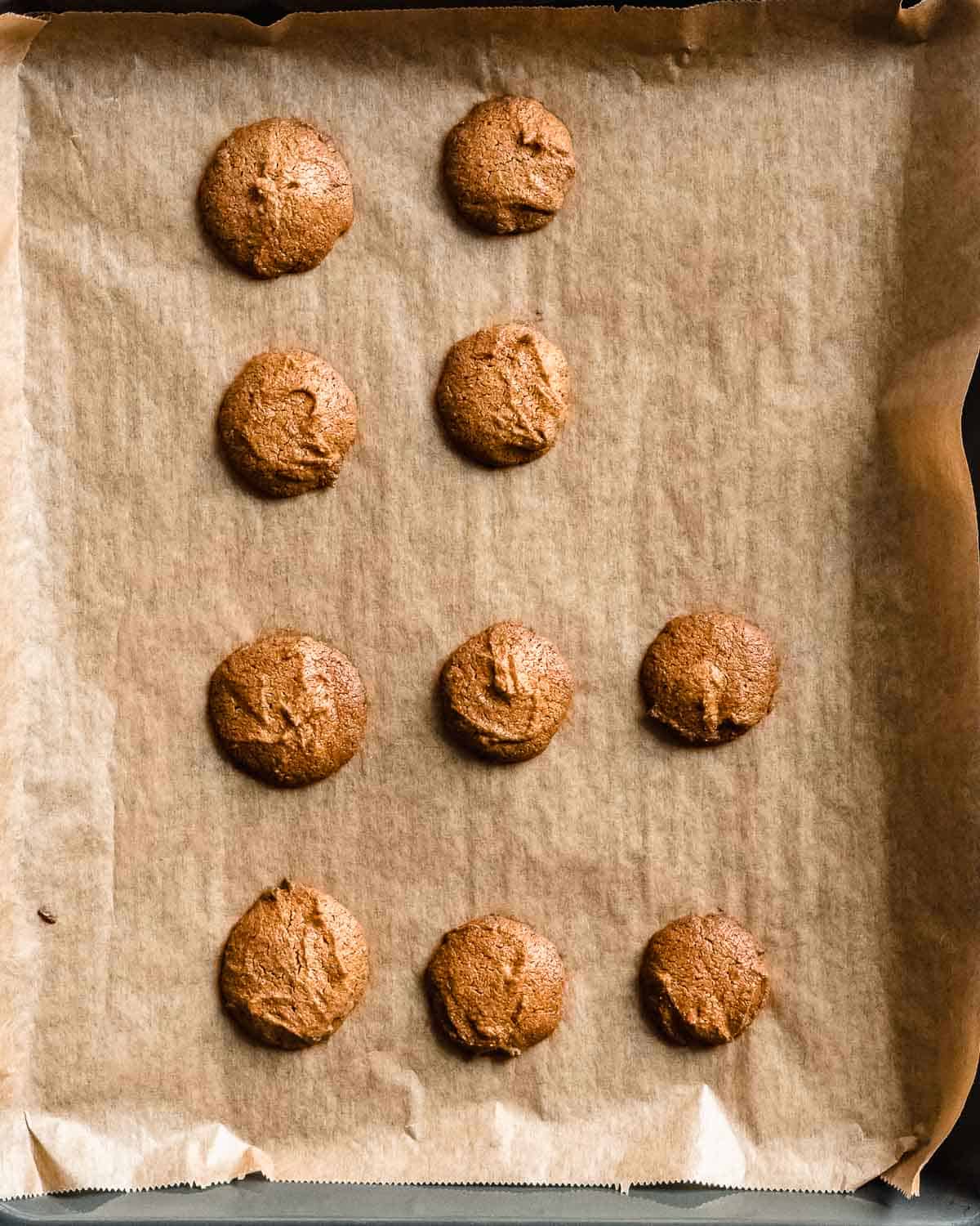 10 baked peanut butter cookies on a baking tray with parchment paper.