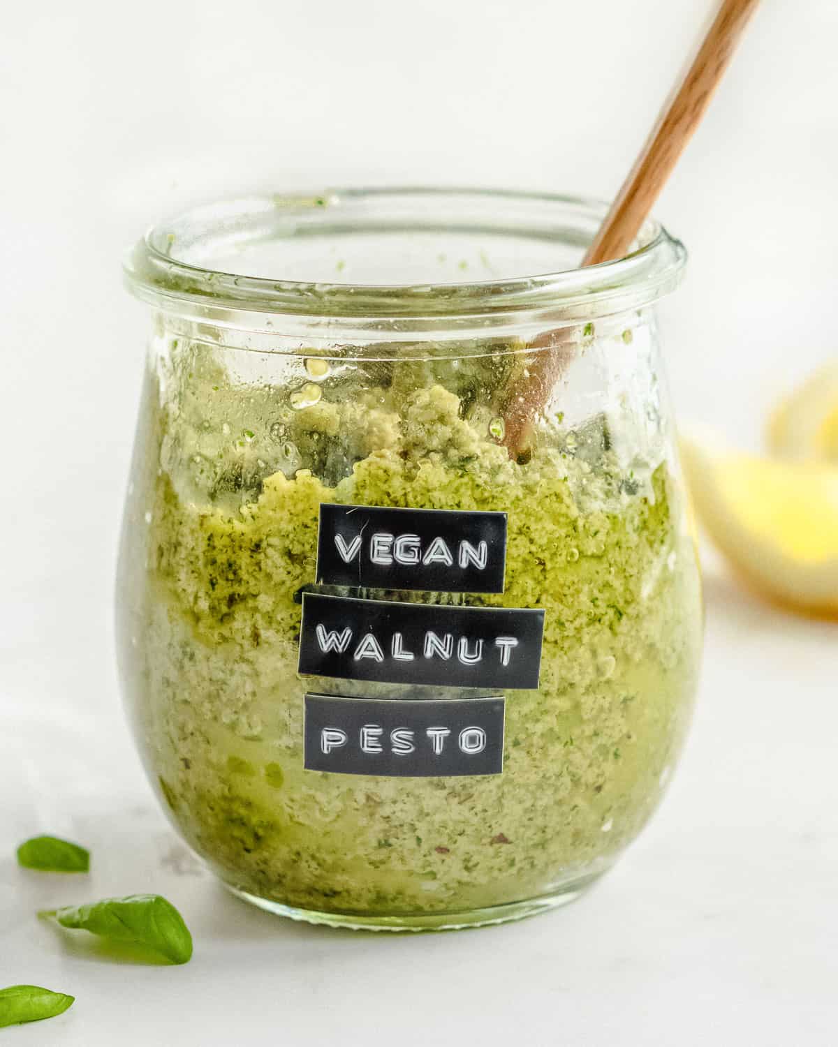 big jar of vegan walnut pesto with a wooden spoon in it.