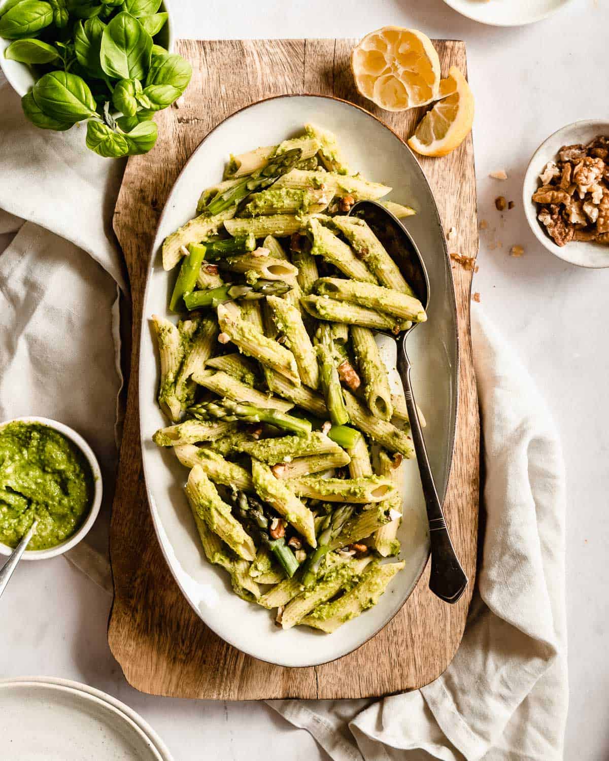 big plate of penne pasta topped with walnut pesto and cooked asparagus.