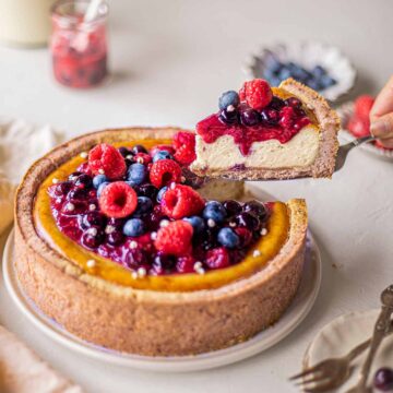 baked vegan cheesecake with berries on top on a plate.