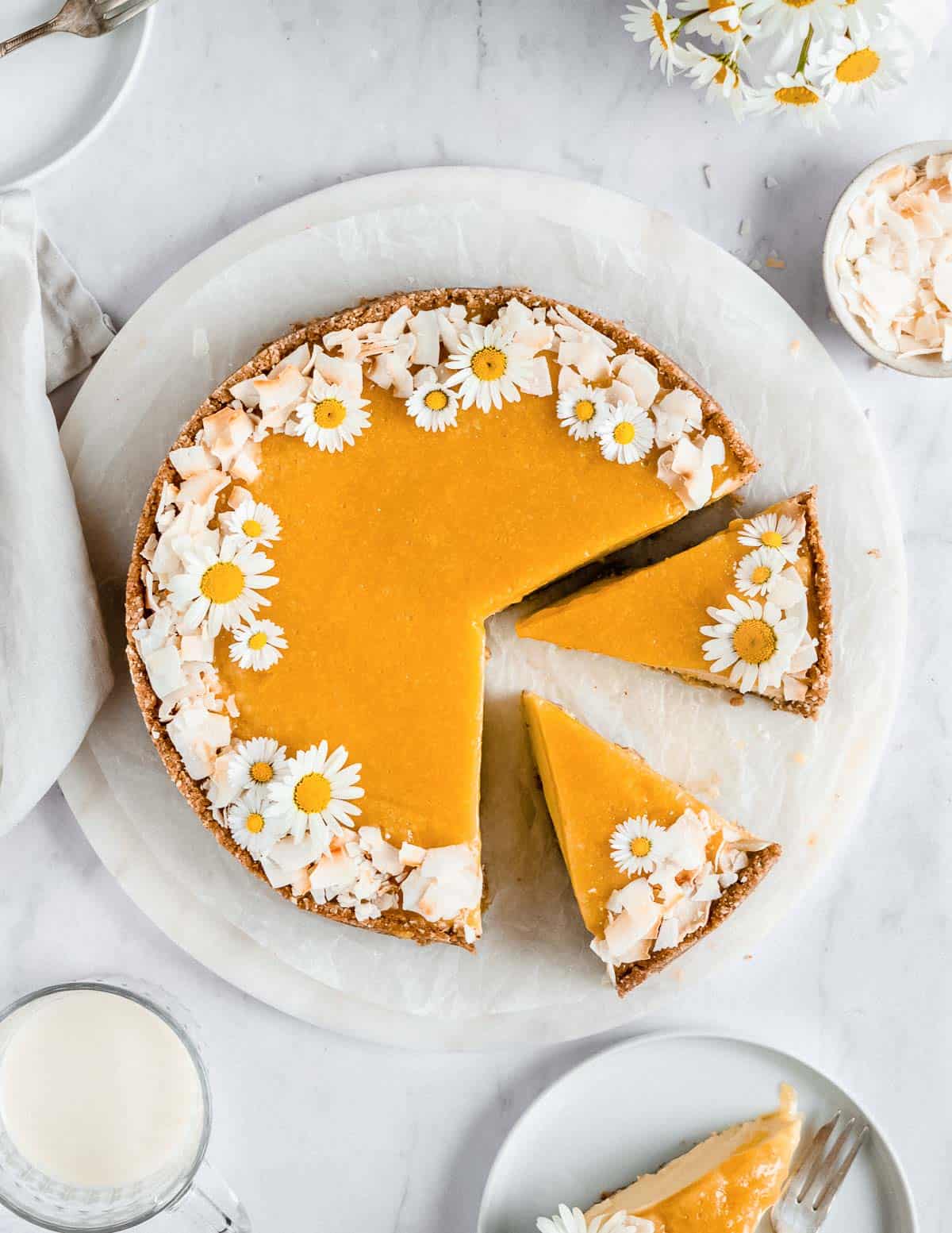 whole no-bake mango cheesecake on a plate with 3 slices next to it.