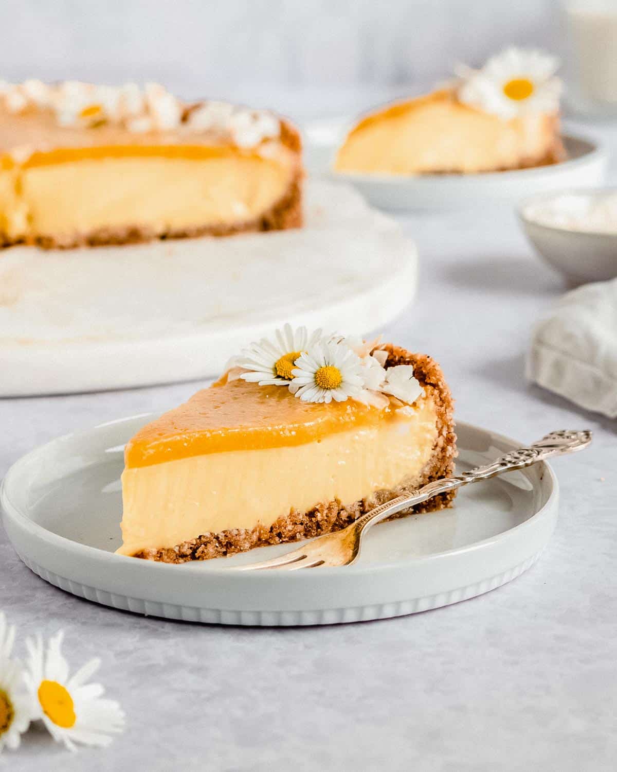 1 slice of mango cheesecake on a plate with a fork next to it.