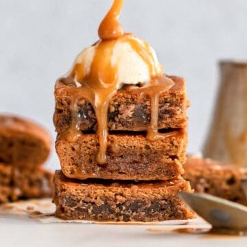 stack of3 peanut butter brownies topped with ice cream and caramel sauce.
