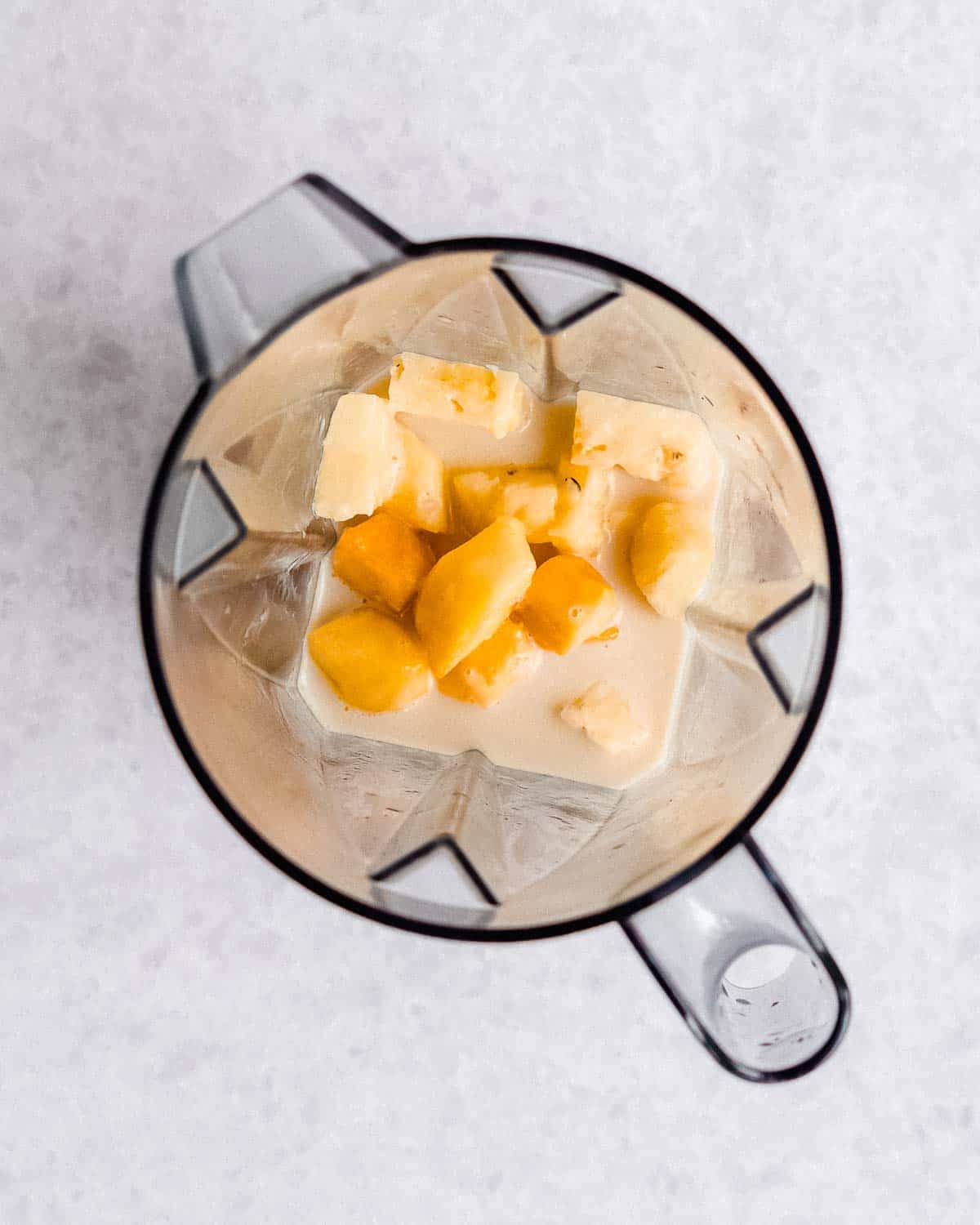 frozen mango chunks, pineapple chunks and oat milk in a blender.