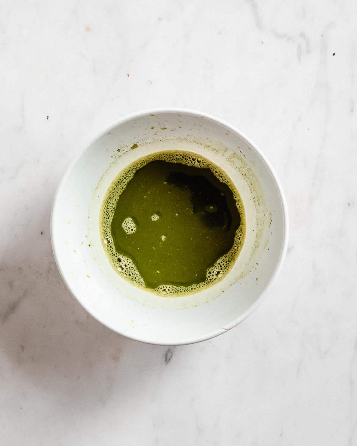 matcha latte whisked together with water in a bowl.