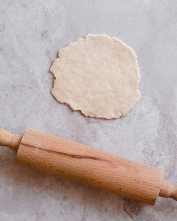 naan bread rolled out, next to it a rolling pin.