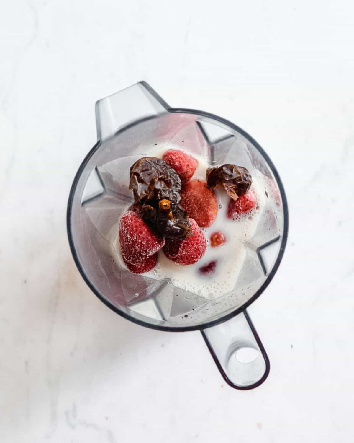 frozen strawberries, medjool dates and plant milk in a blender.