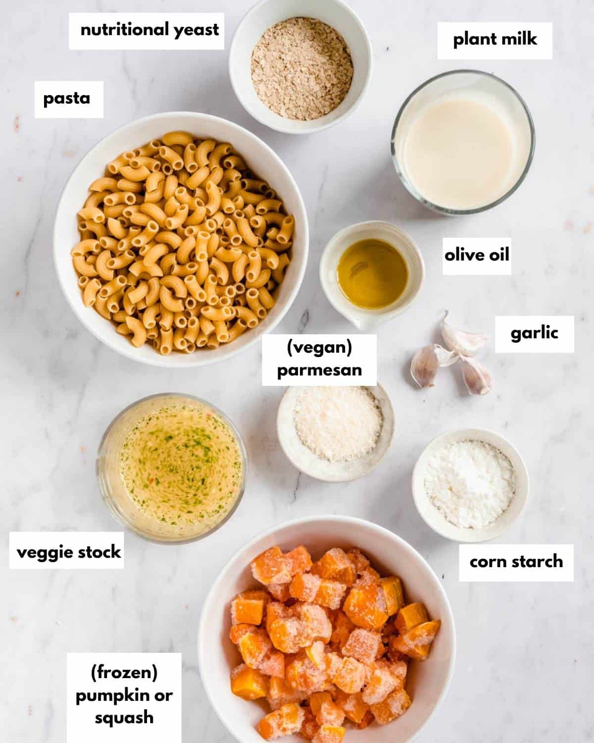 all ingredients for mac and cheese: pasta, nutritional yeast, plant milk, olive oil. garlic, vegan parmesan, corn starch, veggie stock, frozen pumpkin or squash.