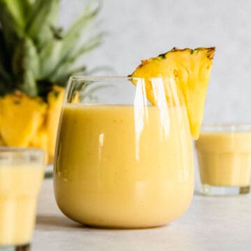 pineapple almond milk smoothie in a serving glass garnished with a pineapple slice.