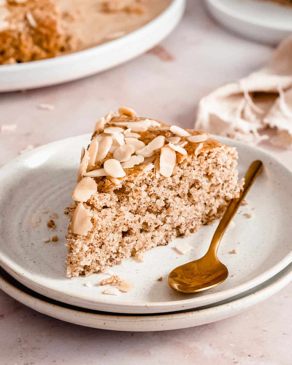 slice of eggless almond cake on a plate.