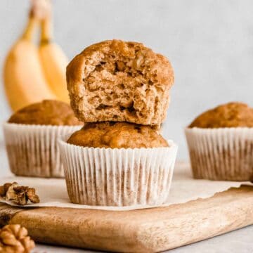 stack of 2 applesauce banana muffins on a wooden board.