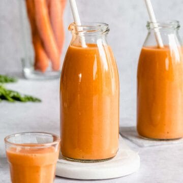 2 glasses of carrot smoothie with a straw.