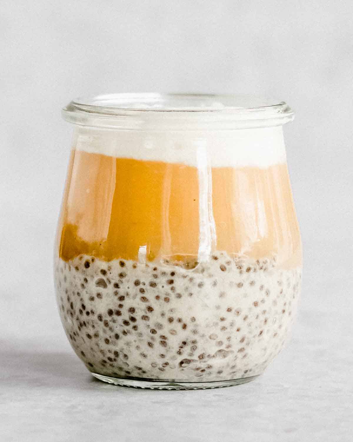 ⅓ of a serving glass filled with apple chia seeds, followed by some applesauce and Greek yogurt.