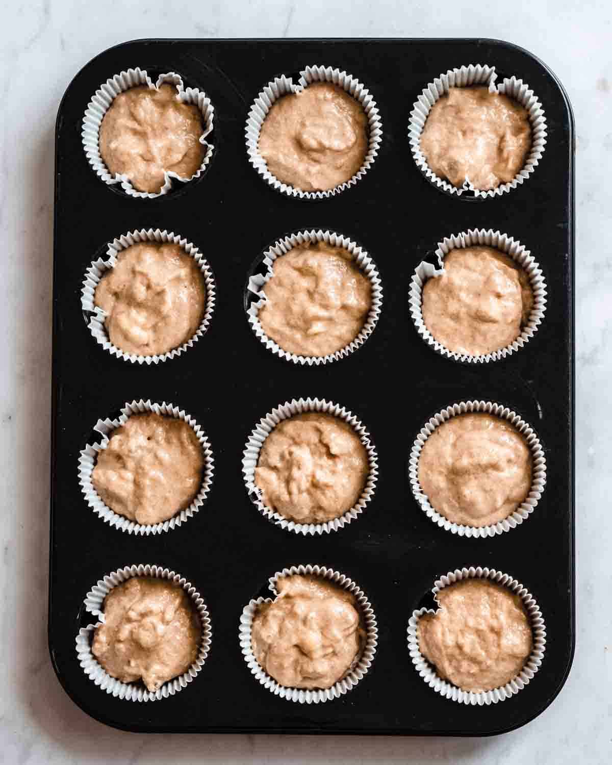muffin batter added to 12 muffin liners in a muffin tin.