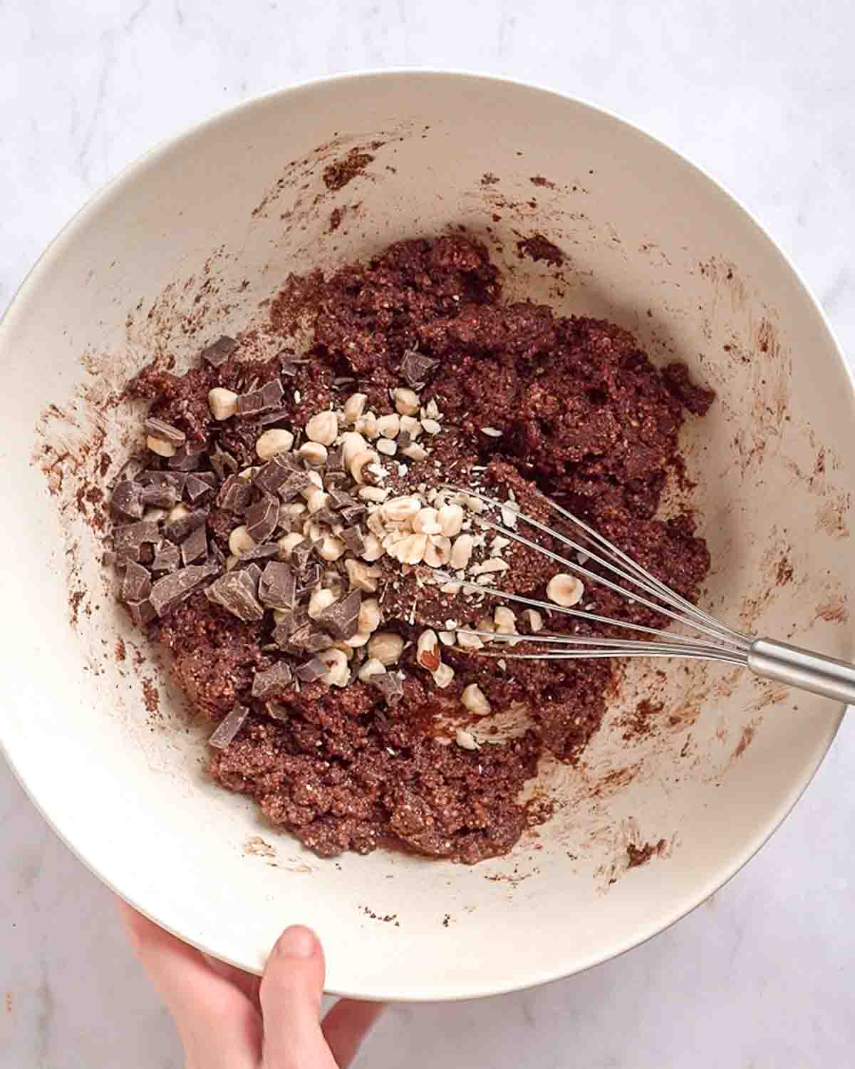 hazelnuts and chocolate chips added to the cookie dough in a large bowl.