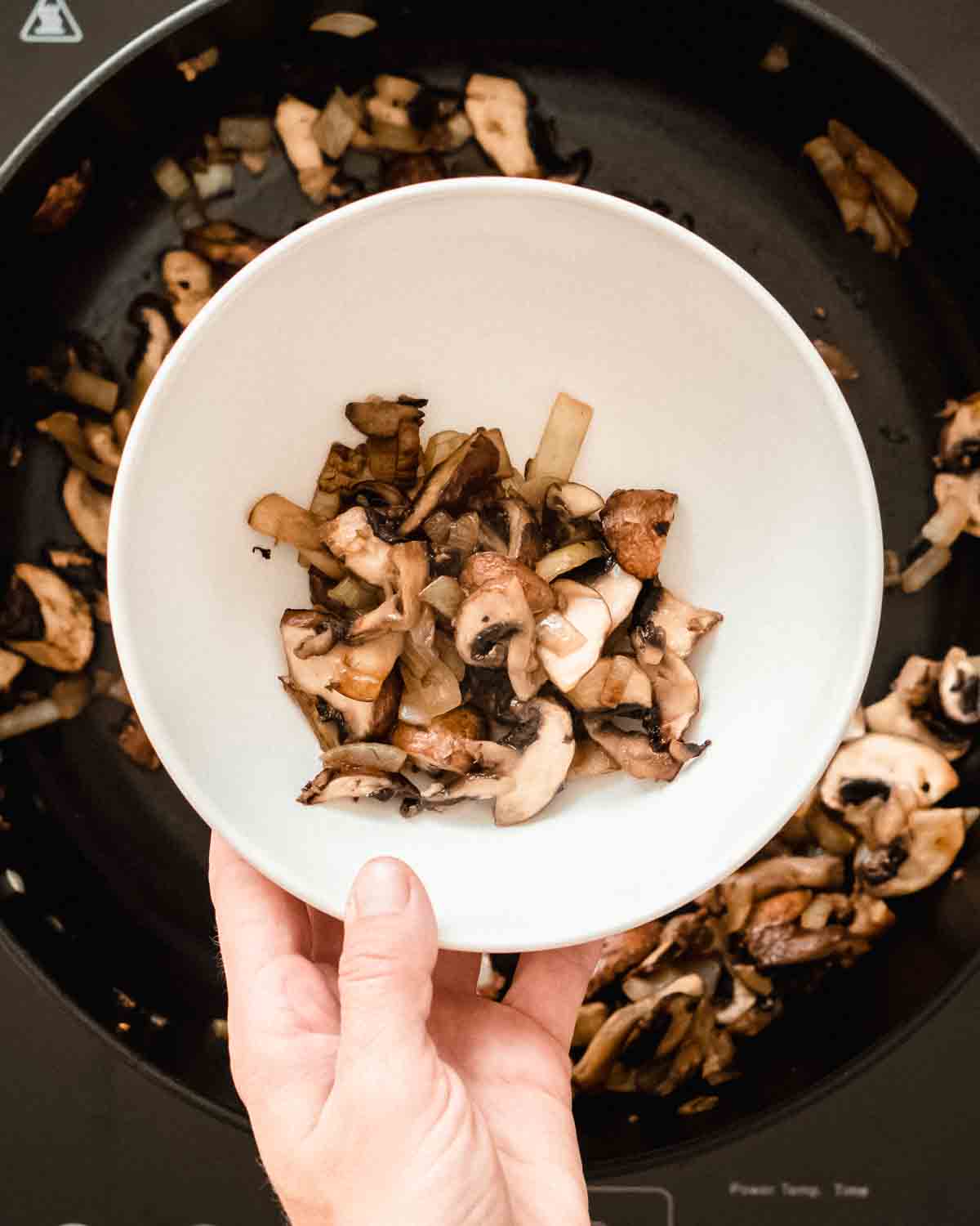 sauteed mushrooms being removed from the pan.