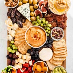 vegetarian charcuterie board filled with cheeses, spreads, nuts, crackers, fresh fruits, dried fruits, raw veggies and grilled veggies.