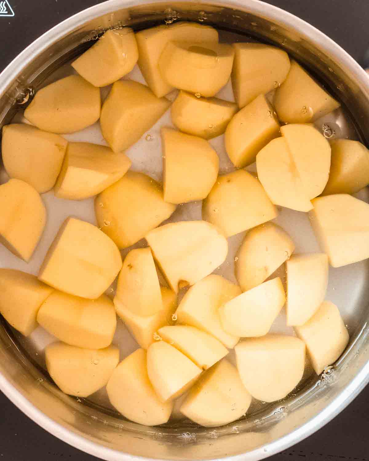 quartered potatotes in a pot with water.