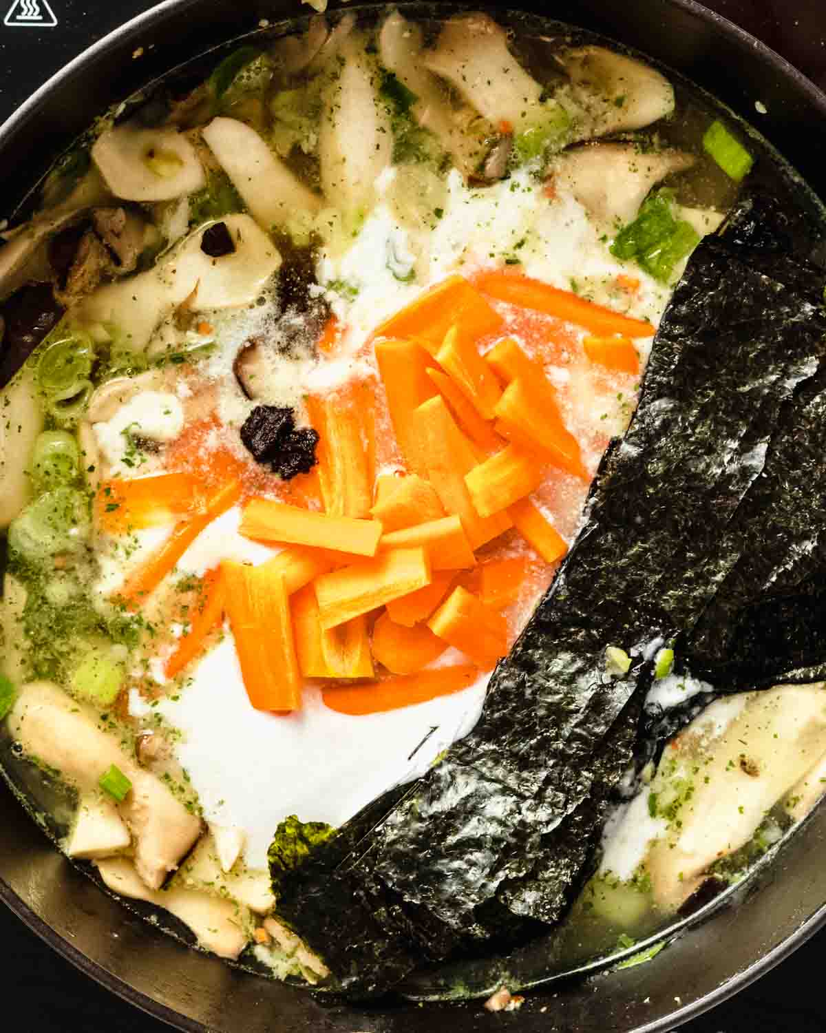 vegetable broth, carrots, coconut milk and nori sheets in a pan.