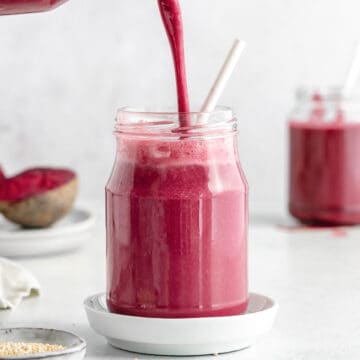 beetroot smoothie being poured into a large glass.