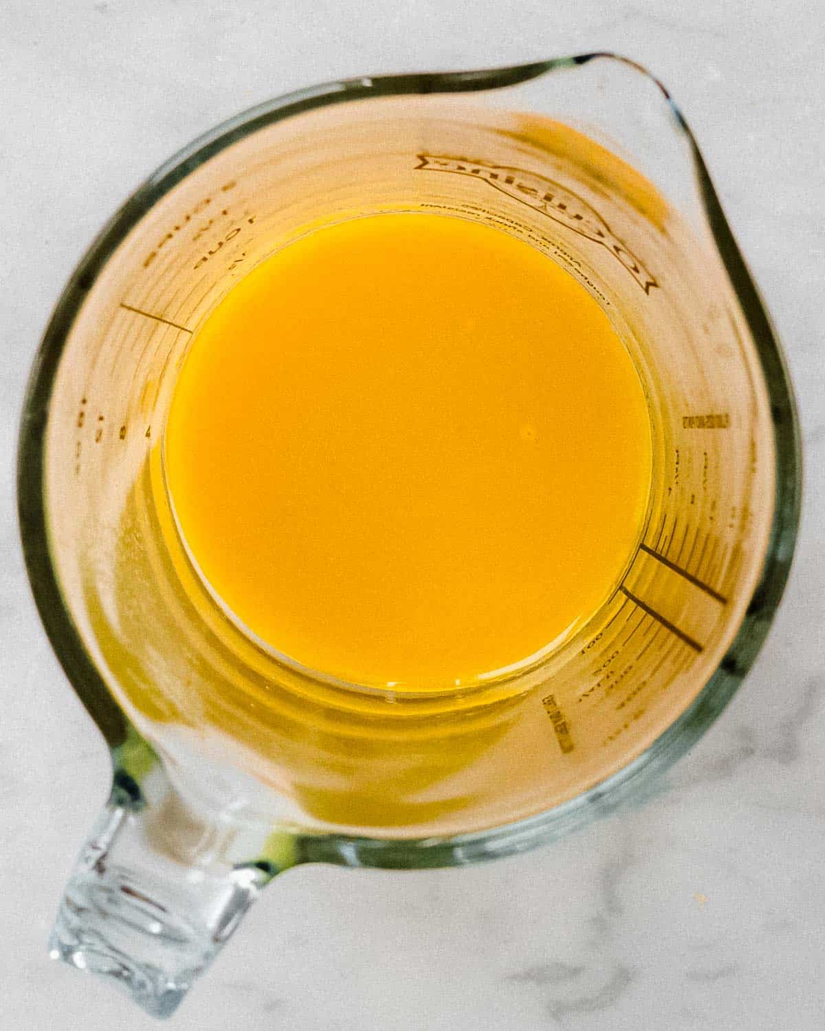 strained lemon ginger turmeric mix in a glass measuring cup.