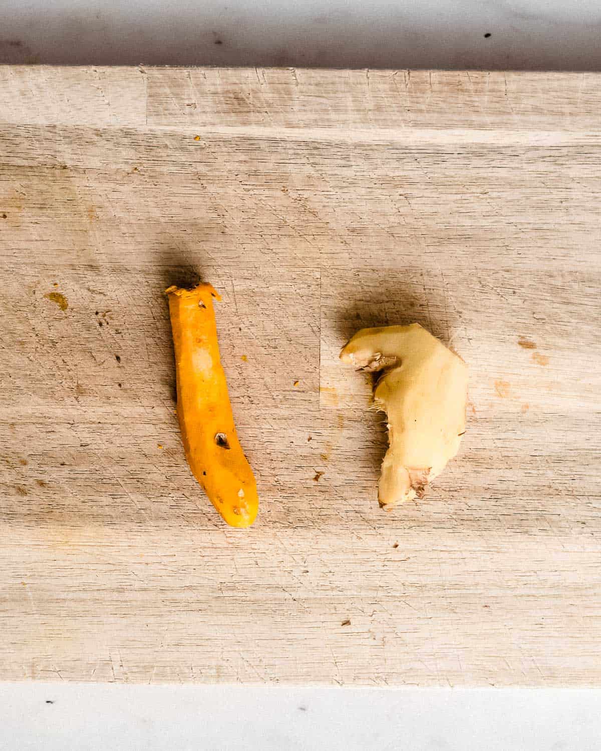 peeled turmeric and ginger on a cutting board.