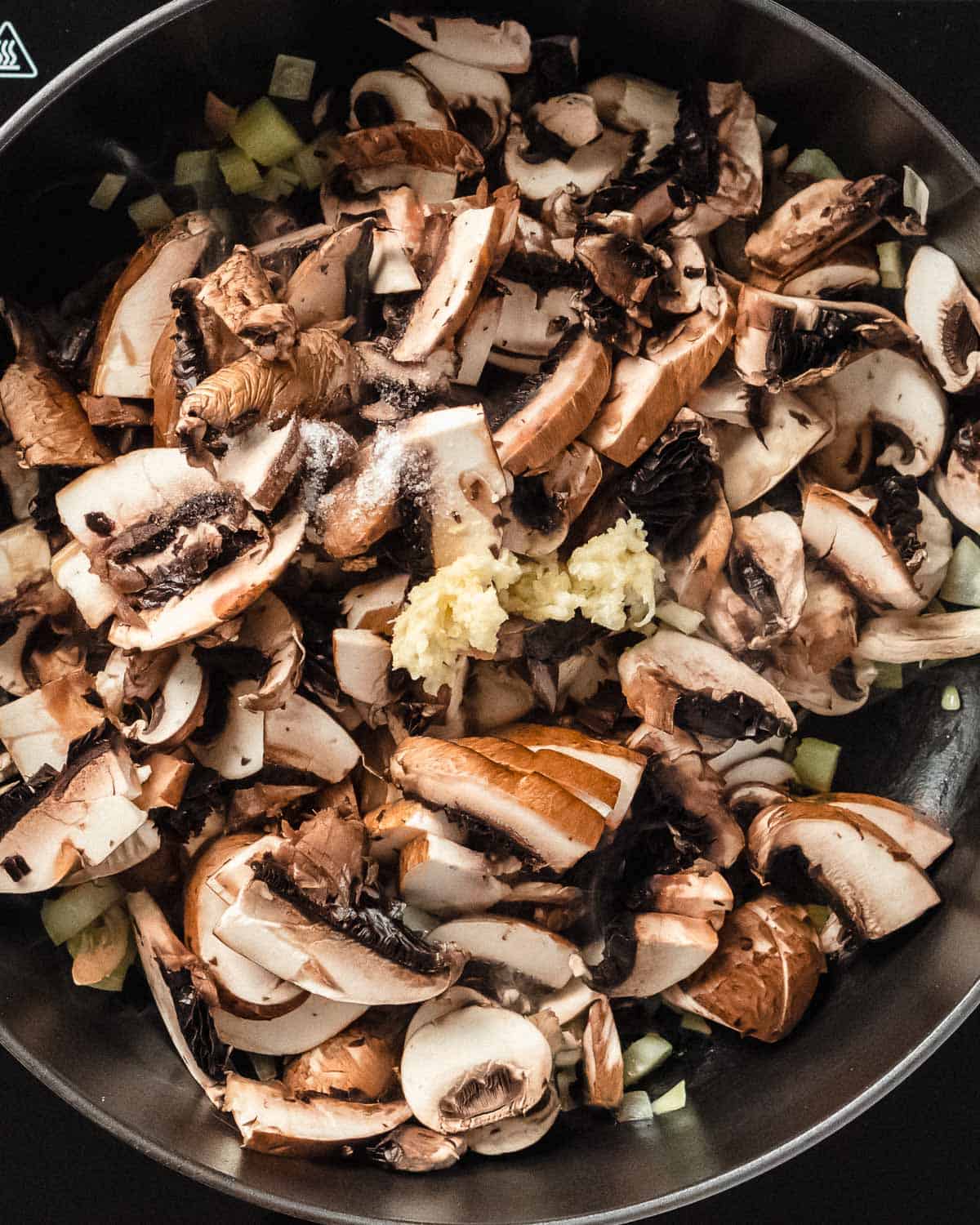 mushrooms, minced garlic and salt added to the sauteed celery in a pan.