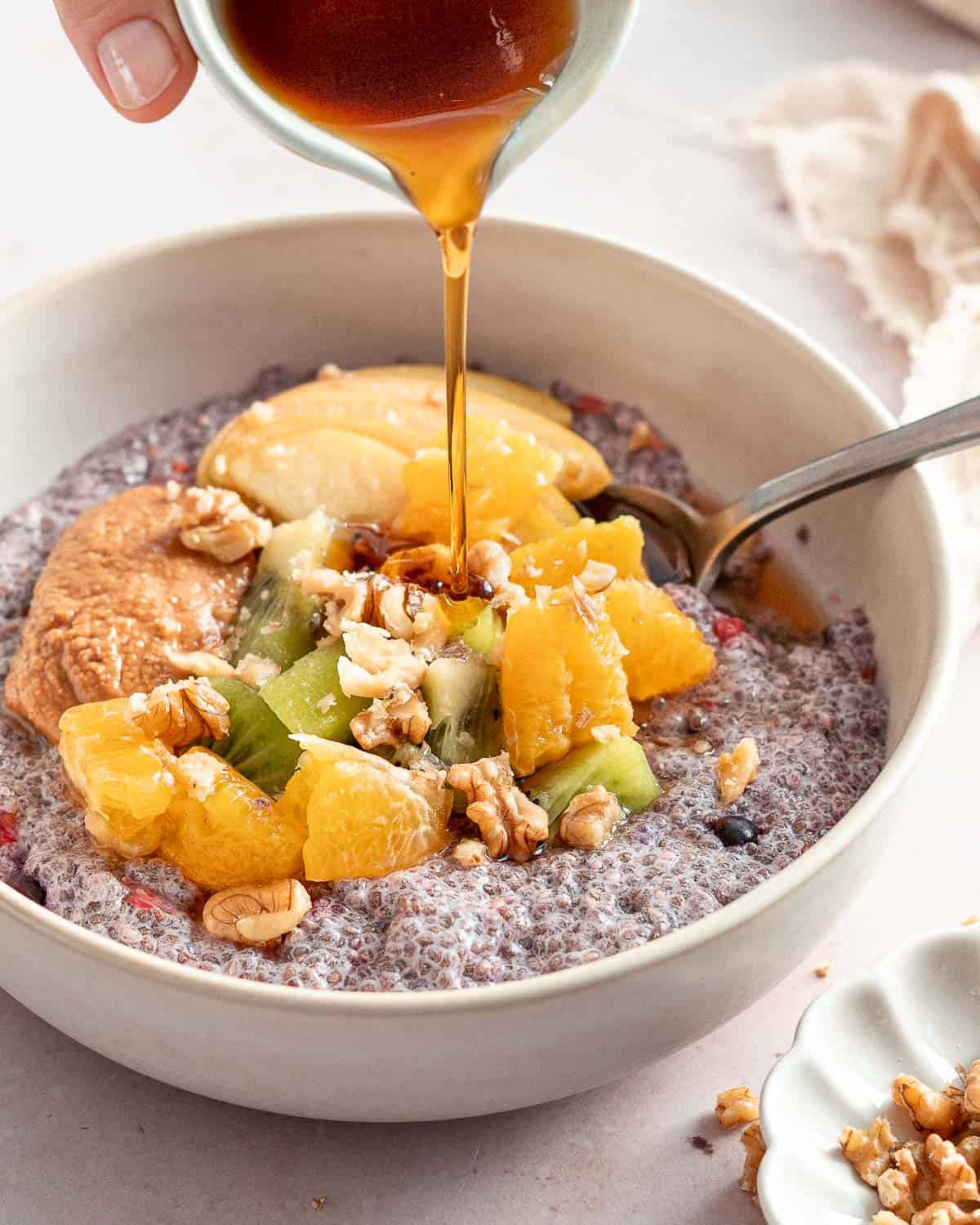 breakfast bowl of chia pudding topped with fresh fruit, walnuts and maple syrup.