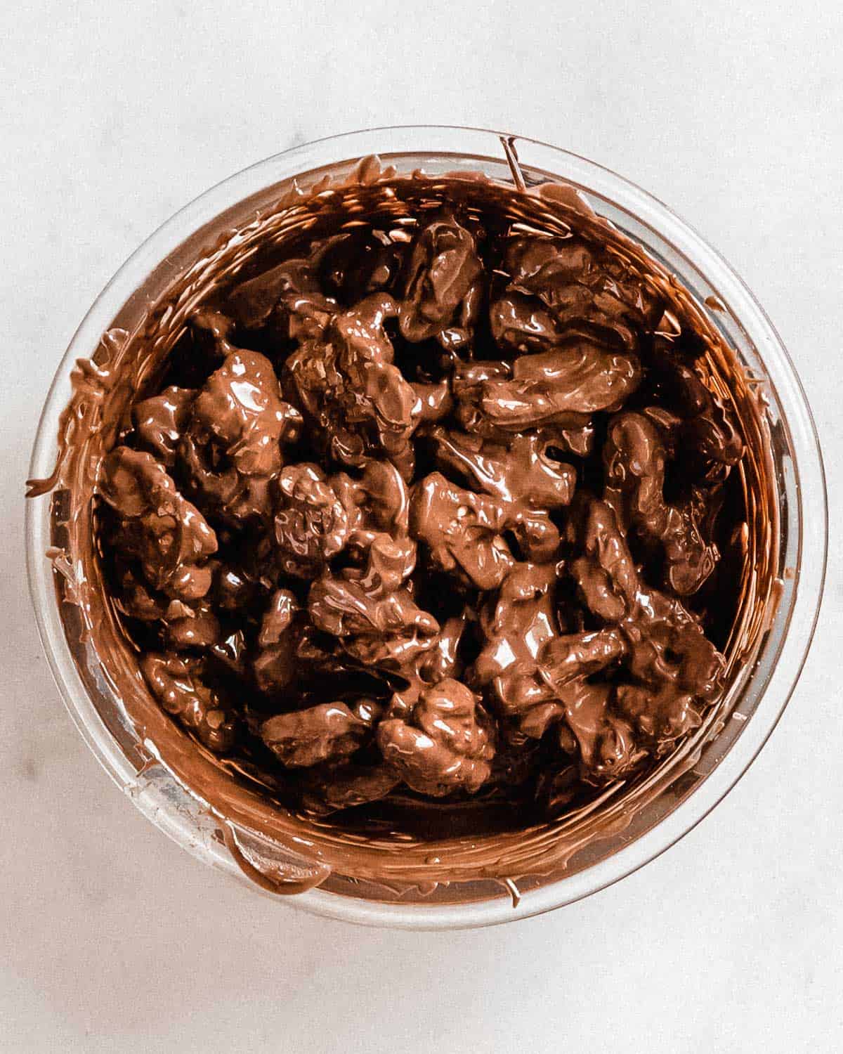 walnuts tossed in a bowl of melted chocolate.