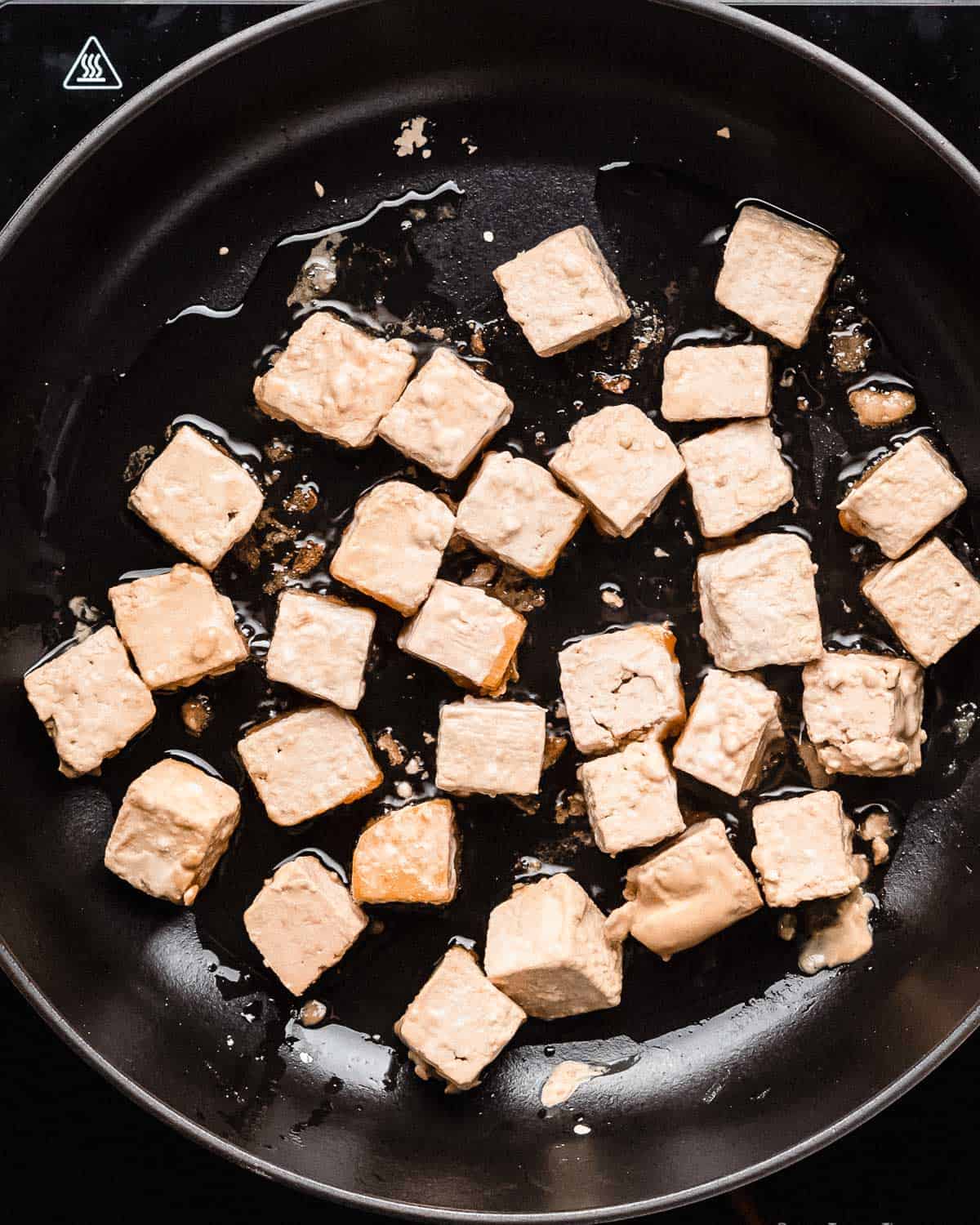 tofu cubes in a pan being fried.