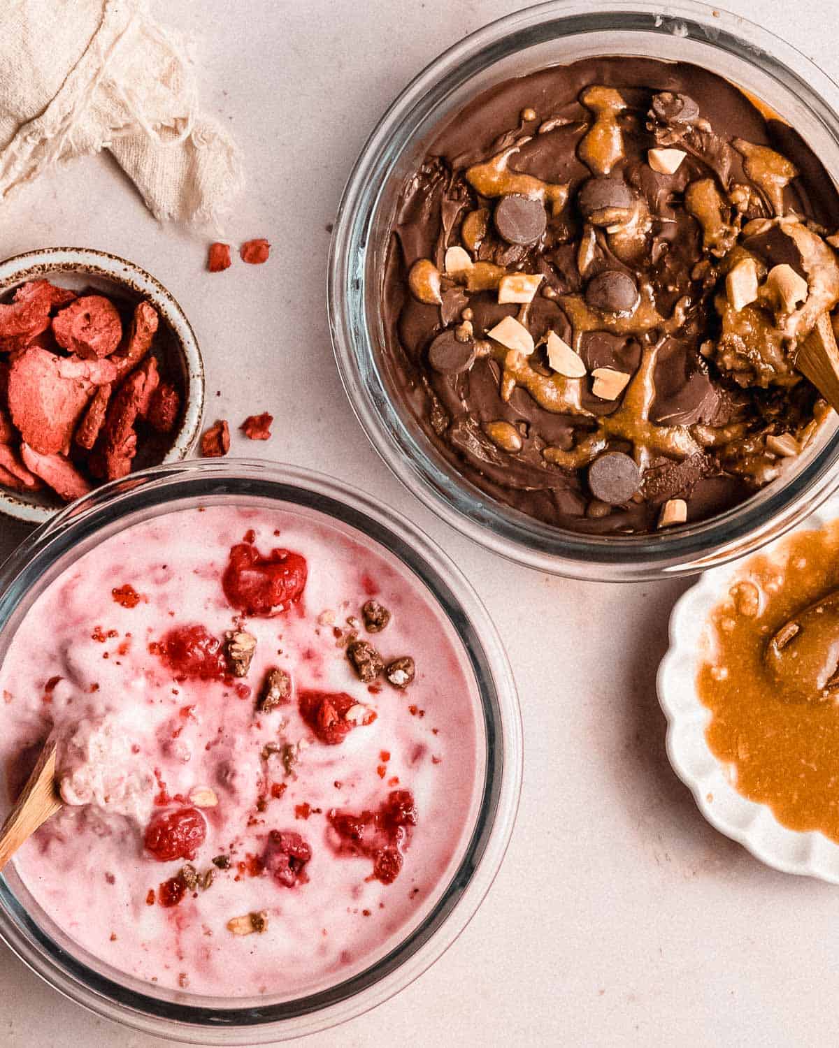 2 bowls of overnight weetabix, one topped with yogurt and rasperries, the other one topped with chocolate.