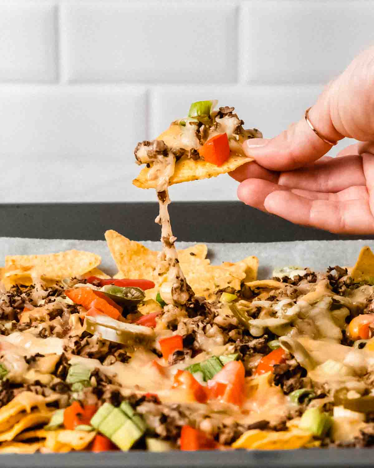 one loaded nacho being pulled out from the other nachos.