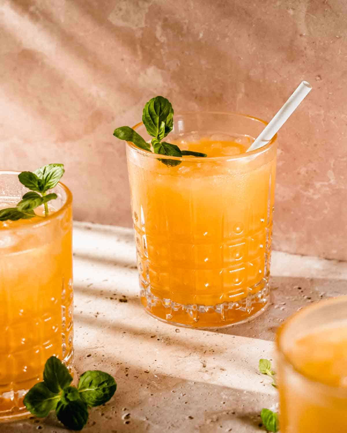 3 glasses of mango mocktail topped with fresh mint and a straw.