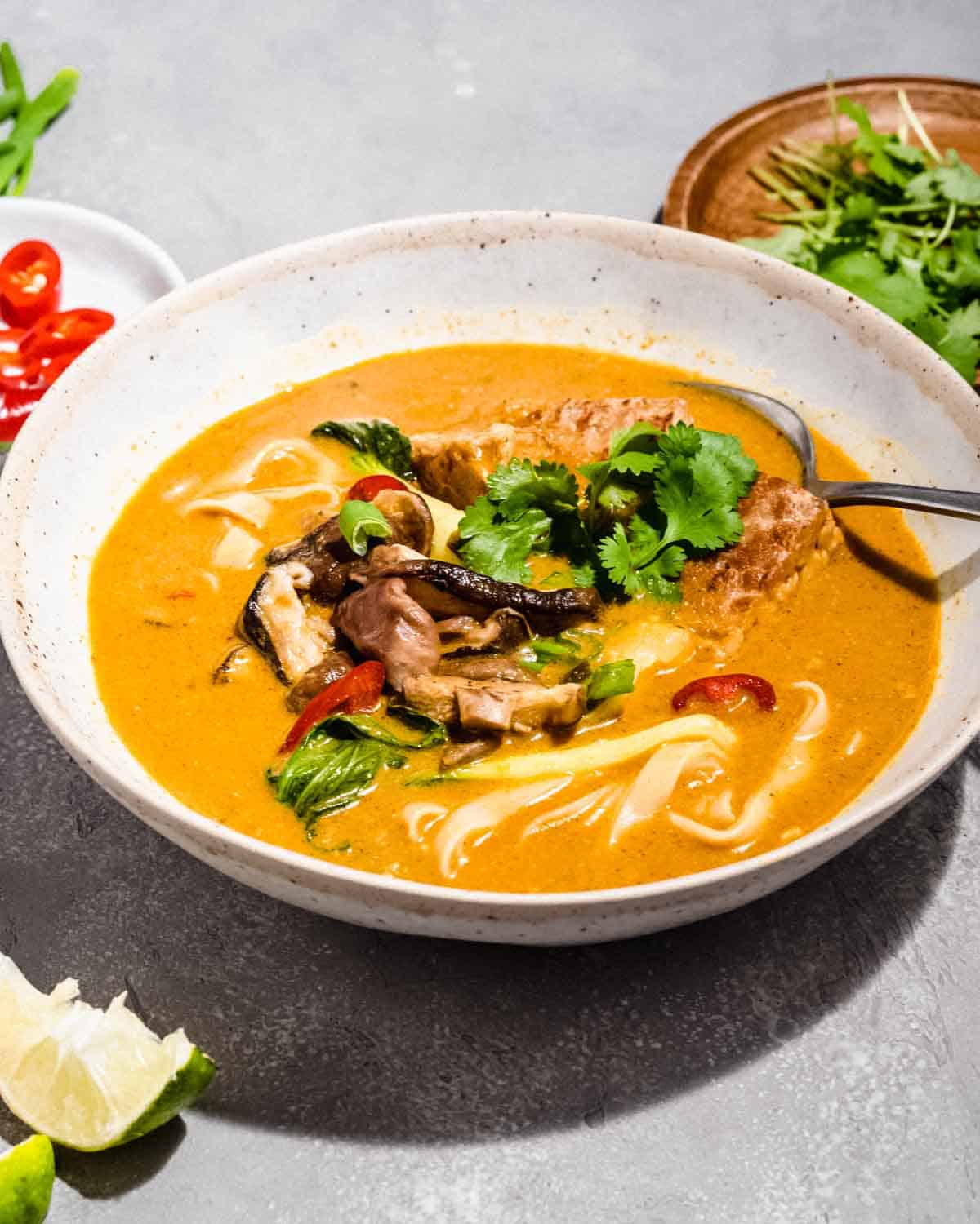 vegetarian laksa topped with noodles, shiitake mushrooms, bok choy, fresh chilies, tempeh and fresh cilantro.
