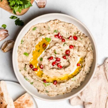 baba ganoush in a small bowl topped with olive oil and pomegranate seeds.
