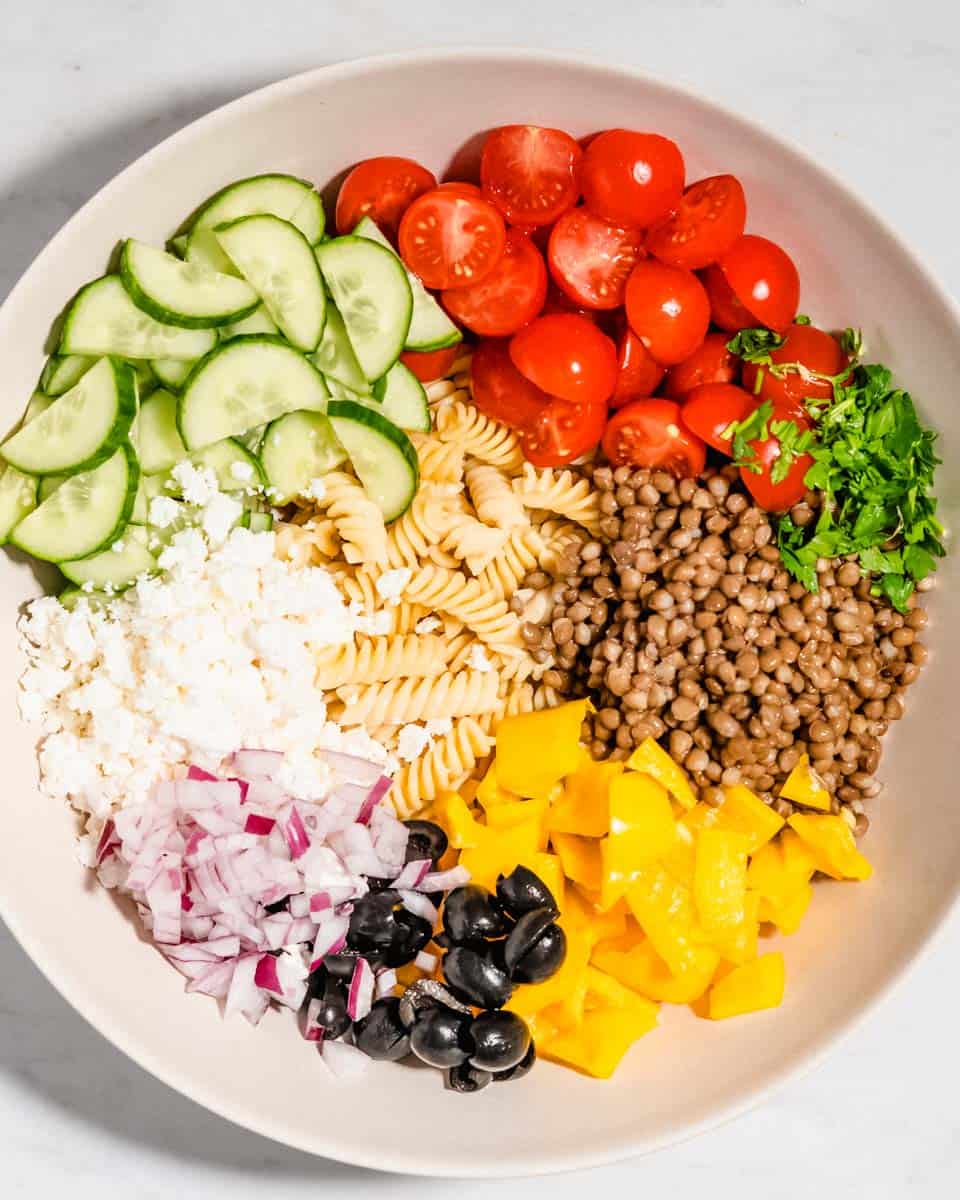 All ingredients for pasta lentil salad in a bowl.