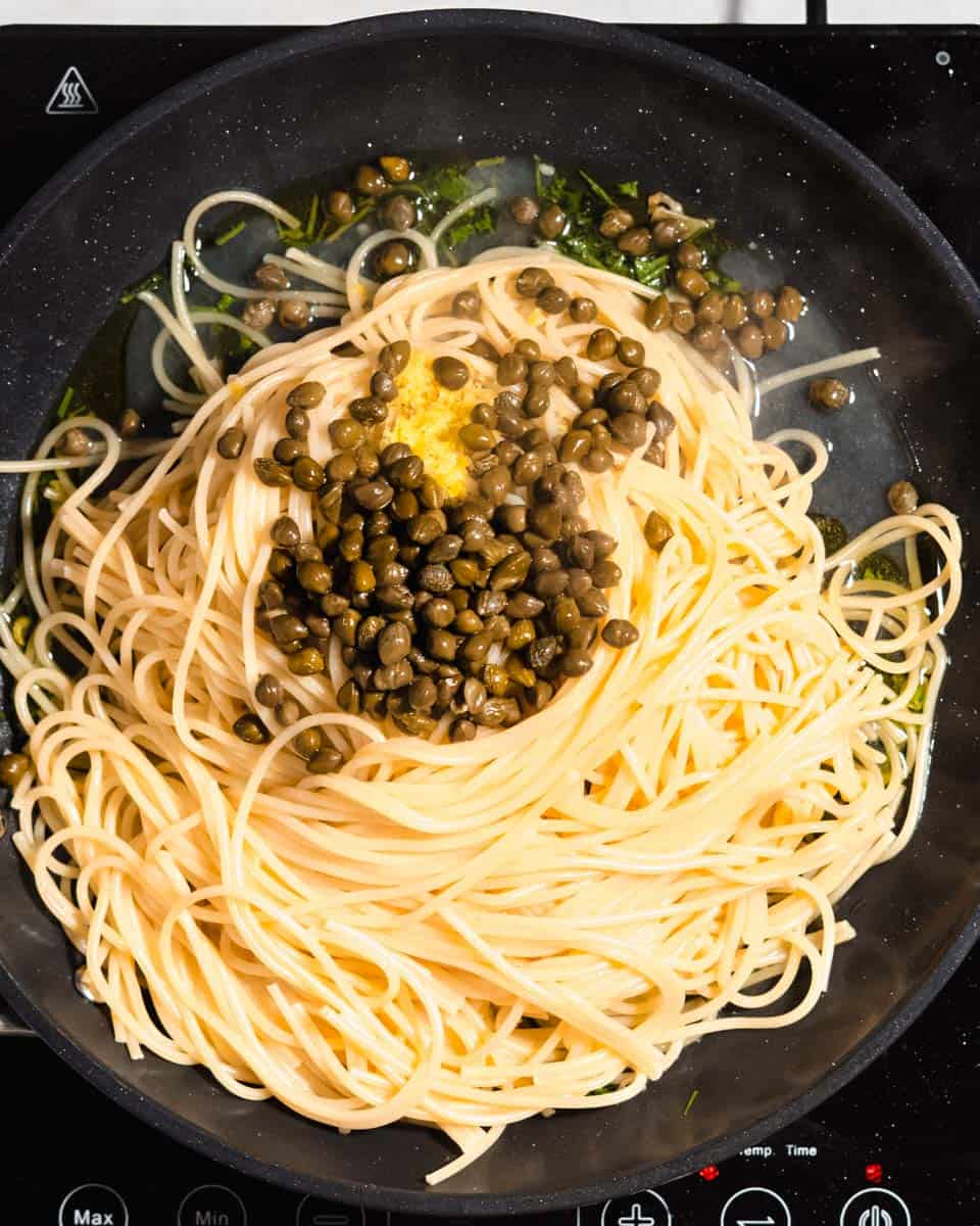 Pasta, capers and lemon zest added to the fried garlic-parsley mix in a large skillet.