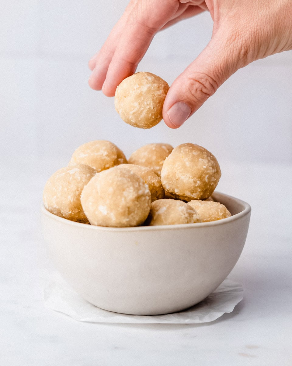 A bowl of protein balls with one ball on the top being taken away.
